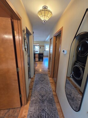 A hallway with wooden doors, a patterned rug, a ceiling light fixture, and a washing machine. - Charming 3-bedroom house in serene Bend with woodsy comfort (Bend)