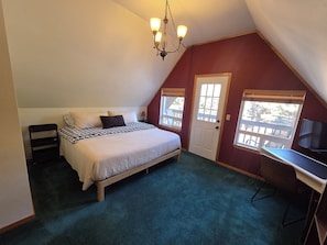 Une chambre à coucher avec un lit, un bureau, une chaise, une porte et une fenêtre.