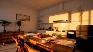 A modern kitchen with a dining table set for four, equipped with a stove, refrigerator, and various kitchen appliances. - Bohemian Chic Villa Brand New 2BR with Private Pool, Next To Obsidian & Paddle (Kabupaten Badung)