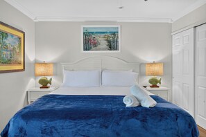 Habitació d'hotel amb un llit, dues taules de nit, un quadre i una porta.