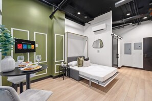 A modern hotel room with a bed, bedside table, and a television displaying a 'Who's watching?' screen. - Experience Downtown Energy Near Petco Park & Dine! (San Diego)