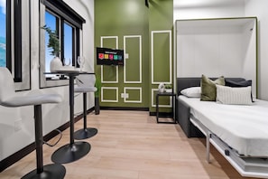 A modern room with a bed, a small table, and a TV displaying a Netflix interface. - Experience Downtown Energy Near Petco Park & Dine! (San Diego)