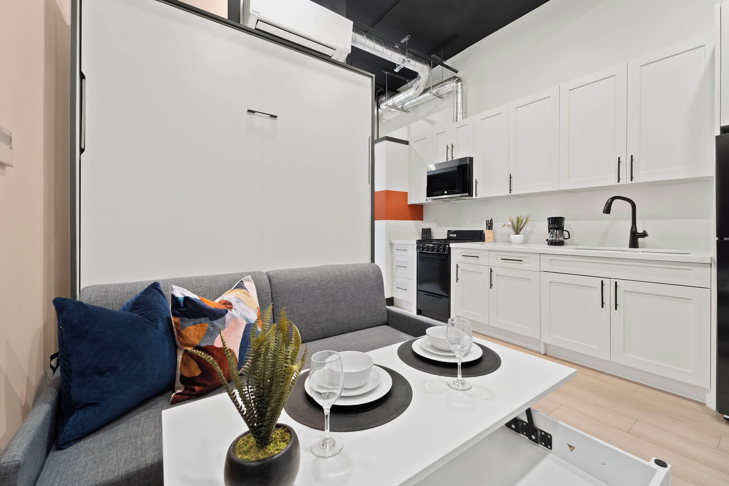 Een moderne keuken met witte kastjes, een zwarte magnetron en een koffiezetapparaat.