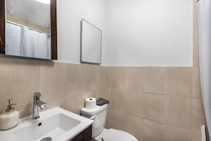A bathroom with a sink, mirror, toilet, and shower curtain. - Extra large 4 bedroom 2 bathroom in Manhattan- full kitchen, dining table + more (New York)