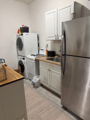A compact kitchen with a stainless steel refrigerator, a washing machine, a toaster, and a sink. - Extra large 4 bedroom 2 bathroom in Manhattan- full kitchen, dining table + more (New York)