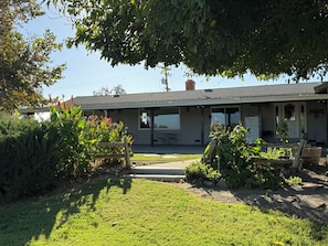 A single-story building with a covered patio area, a small garden, and a clear sky.