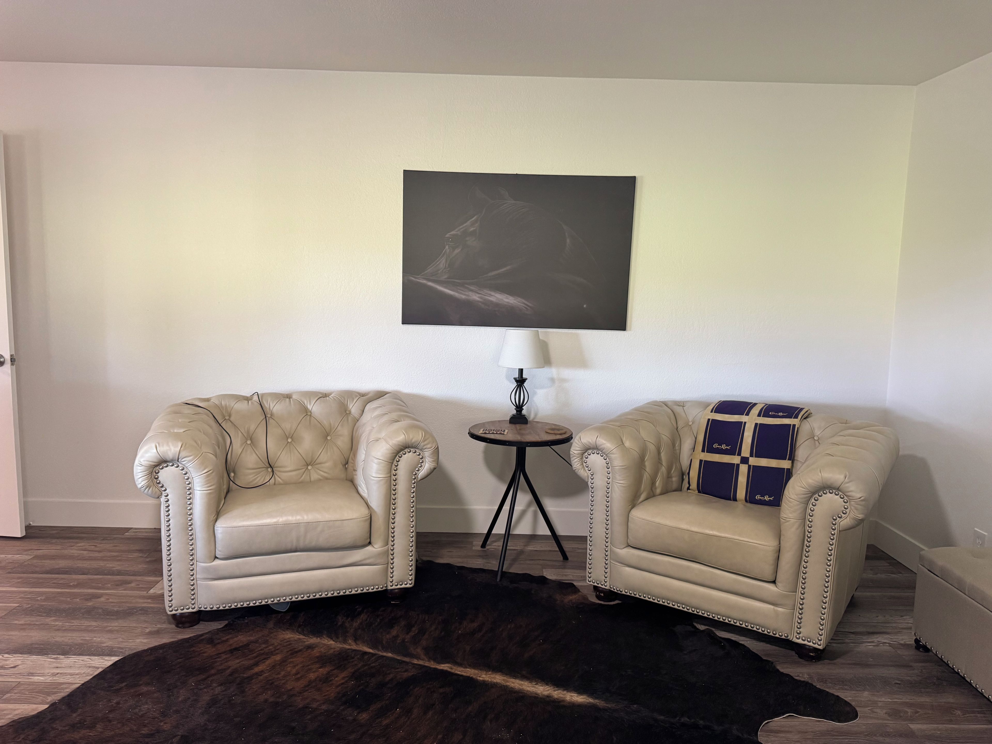 A room with two armchairs, a small round table, a lamp, and a dark rug.