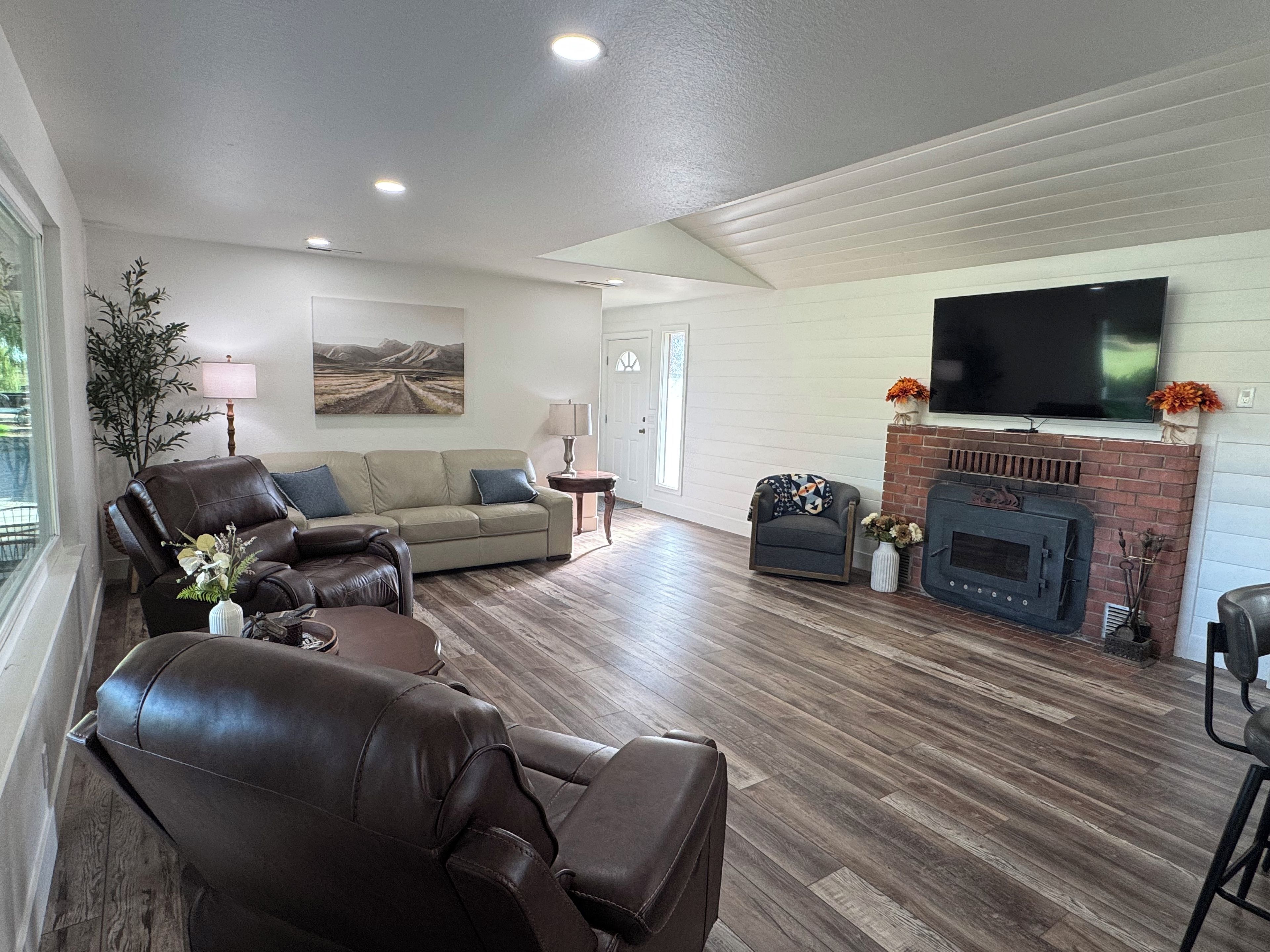 A living room with a leather sofa, a couch, a fireplace, and a flat-screen TV mounted above it.
