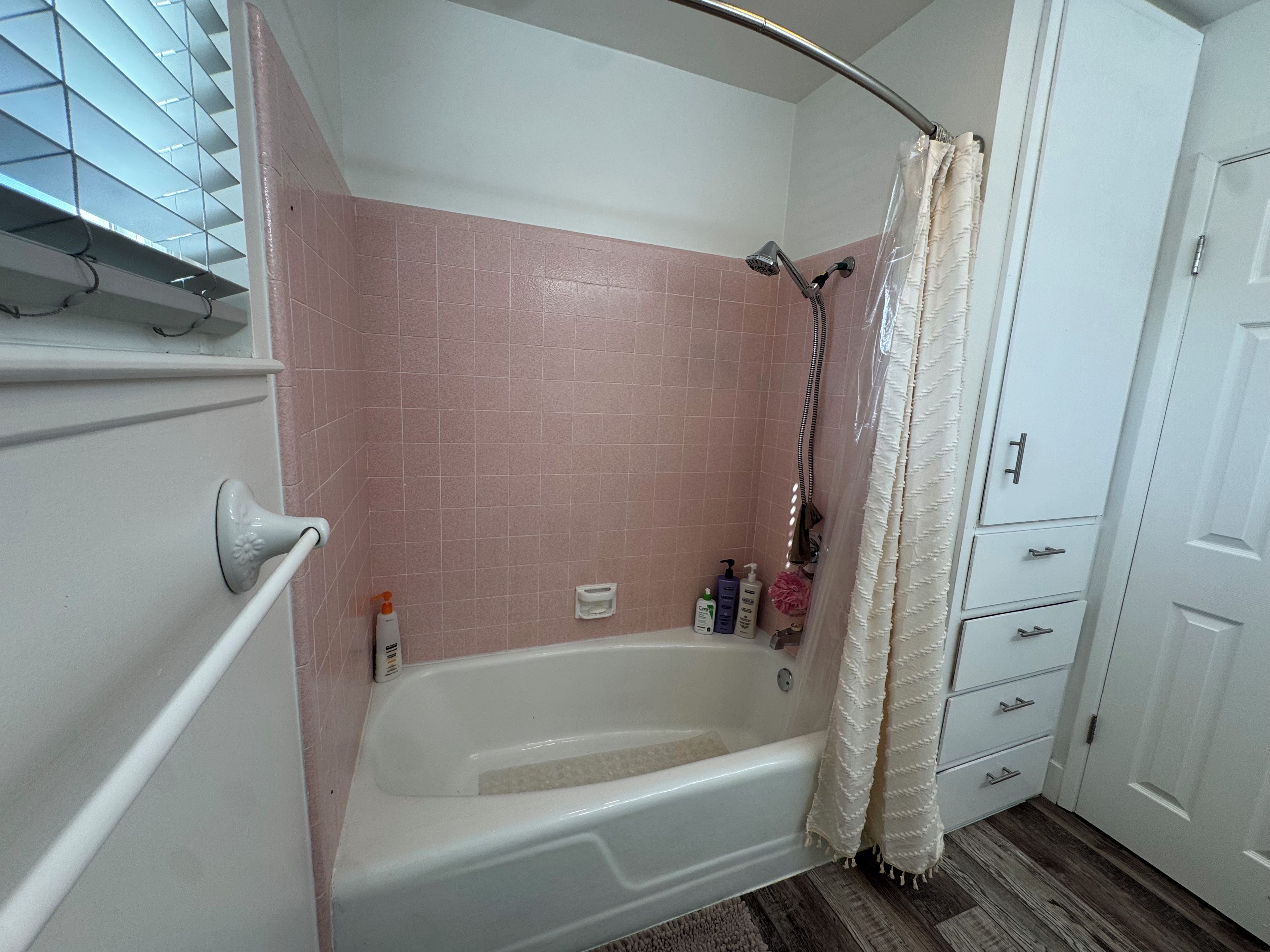 A bathroom with a bathtub, a shower, and a door with drawers.