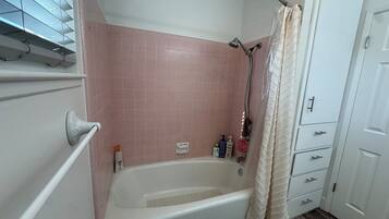 A bathroom with a bathtub, a shower, and a door with drawers.