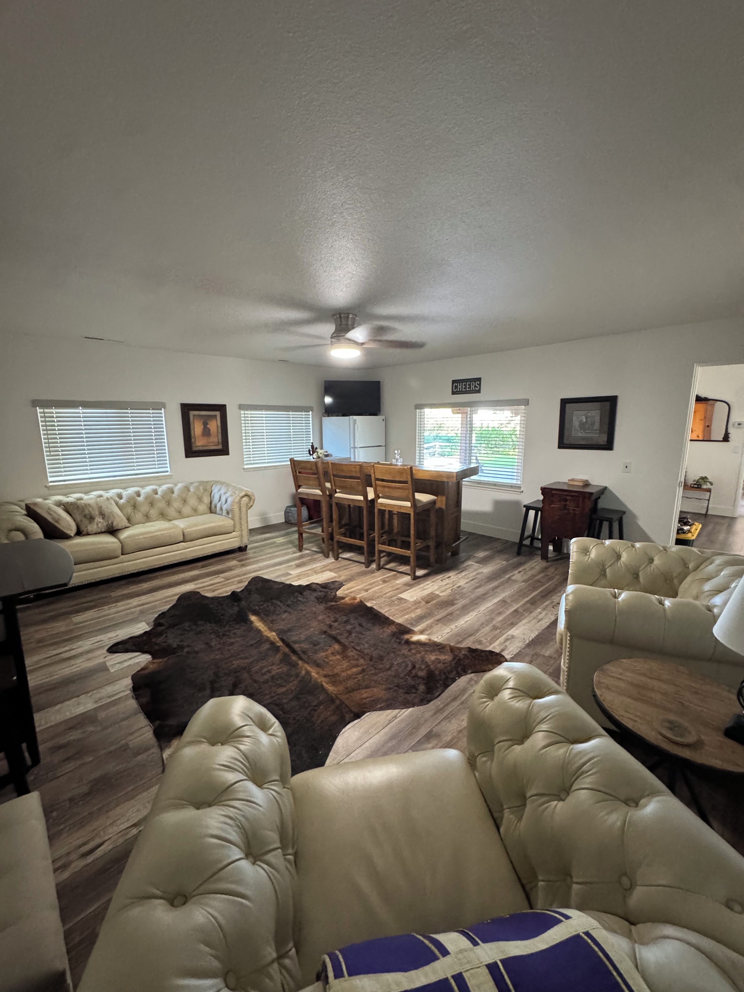 A living room with a sofa, leather chairs, a dining table, and a rug.