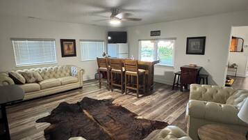 A living room with a sofa, leather chairs, a dining table, and a rug.