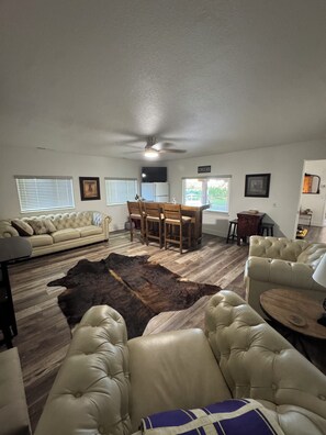 A living room with a sofa, leather chairs, a dining table, and a rug. - Serene 2-bedroom house in Orland perfect for relaxing (Orland)