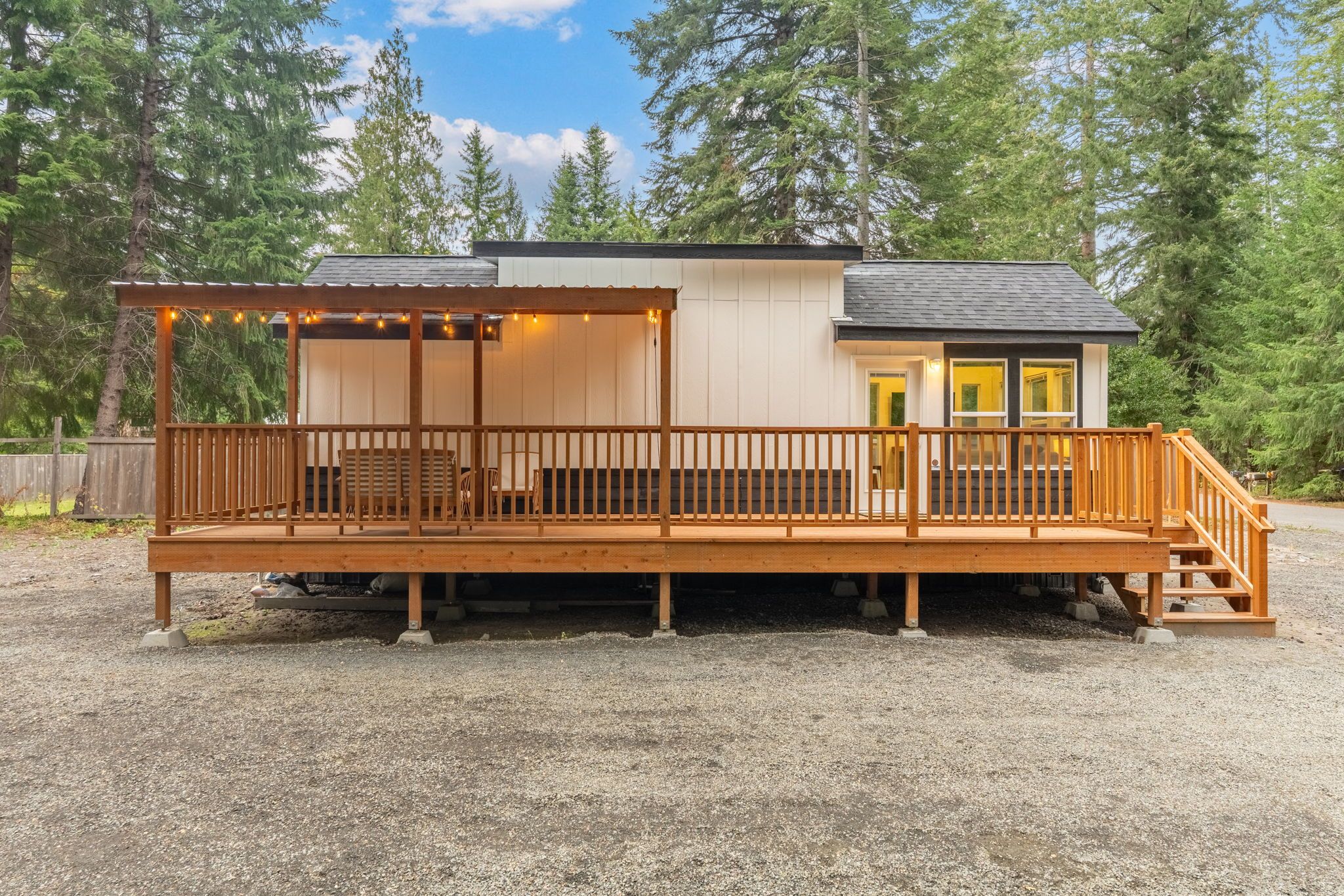 A wooden deck with a covered seating area and a small building with a door and windows.
