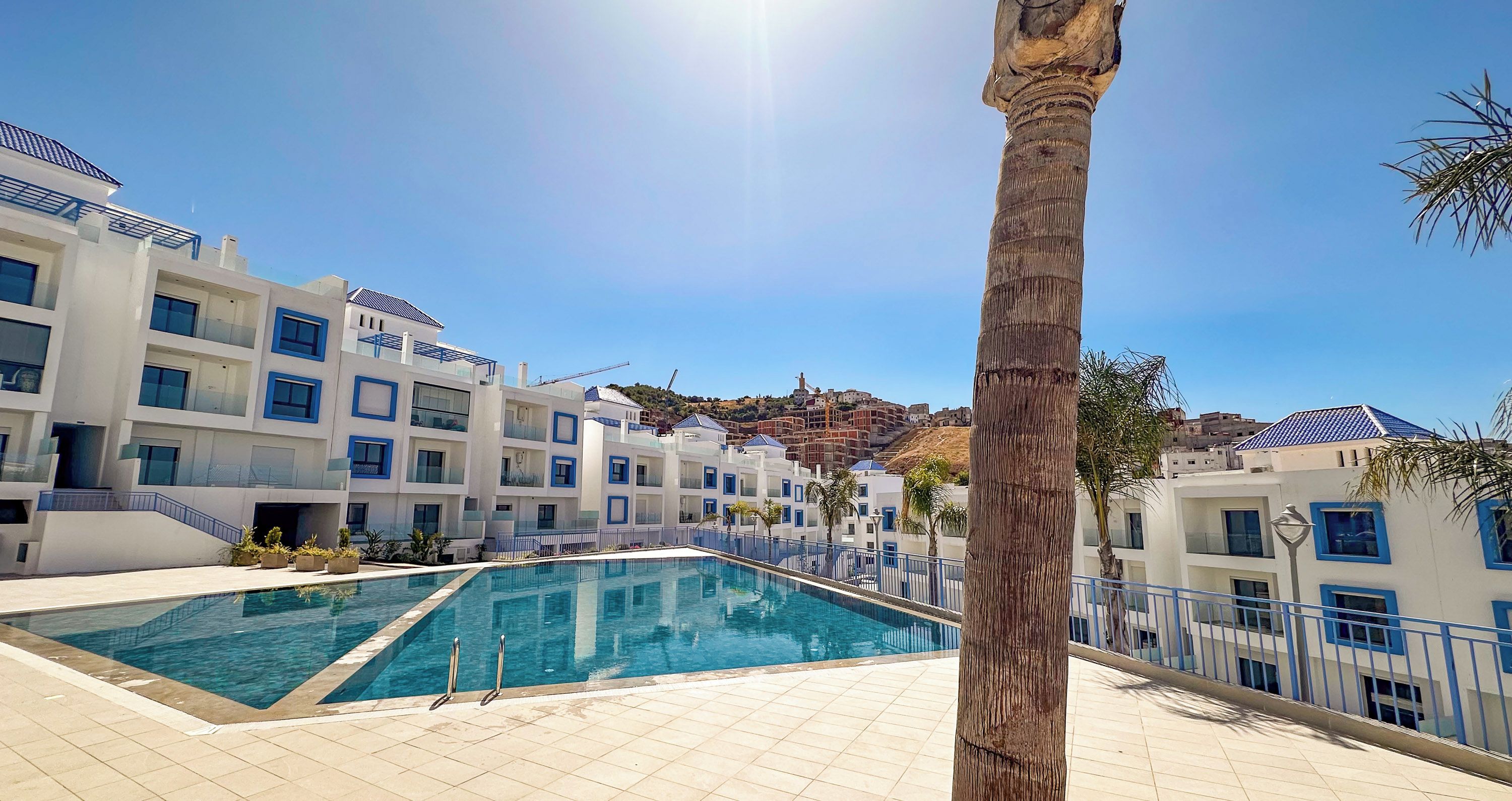 Ein modernes Hotel mit Schwimmbad, mehreren Balkonen und Blick auf die Hügellandschaft.