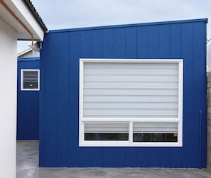 Un bâtiment à l’extérieur bleu, avec une porte de garage blanche et une petite fenêtre.