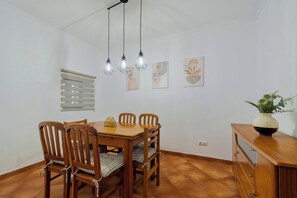 A dining area with a wooden table and chairs, a hanging light fixture, and wall art. - Brisa do Tejo, By Home Match (Alcochete)