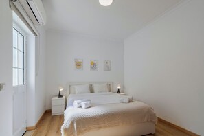 A minimalist bedroom with a bed, bedside lamps, and artwork on the wall. - Brisa do Tejo, By Home Match (Alcochete)