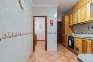A kitchen with wooden cabinets, a stove, and a tiled backsplash. - Brisa do Tejo, By Home Match (Alcochete)