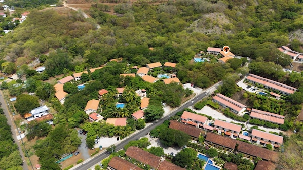 Zona residencial amb diverses cases, algunes amb piscines, envoltada de vegetació abundant.