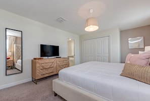 A bedroom with a bed, a dresser, a television, a door, and a mirror. - 5 Bed/4.5 Bath Town House Champions Gate Resort! 5 Bedroom Villa (Davenport)