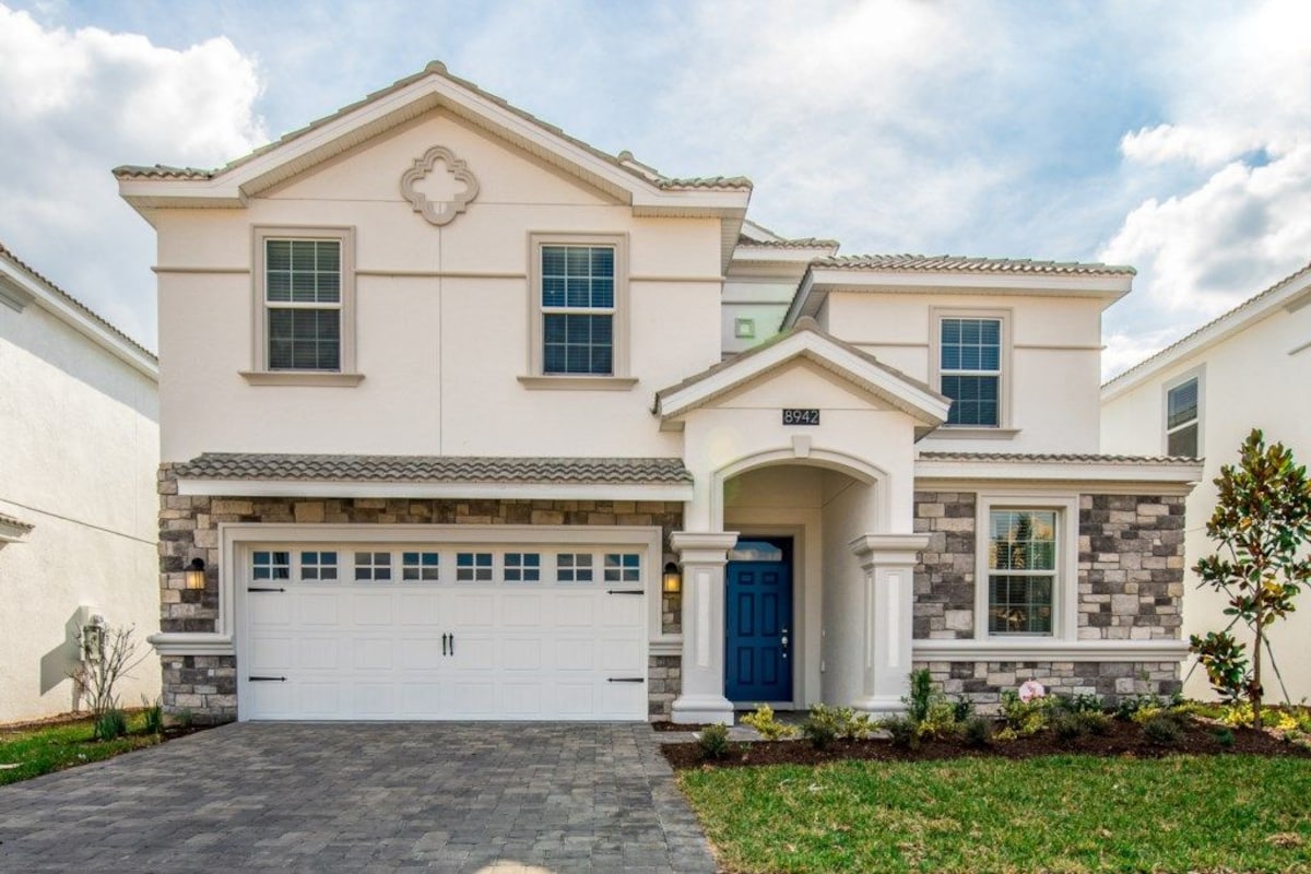 A two-story house with a garage, a blue door, and a stone facade.