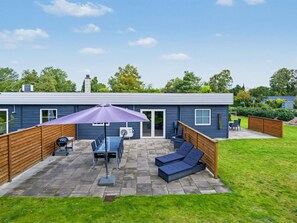 A modern house with a patio area featuring a table, chairs, and a purple umbrella. - "Nina" - 600m from the sea by Interhome (Væggerløse)