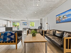 A modern living room with a sofa, coffee table, and a painting of a coastal scene. - "Nina" - 600m from the sea by Interhome (Væggerløse)