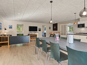 A modern kitchen with a microwave, a dining area with chairs, and a television. - "Nina" - 600m from the sea by Interhome (Væggerløse)