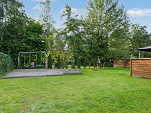 A grassy backyard with a swing set and a wooden structure. - "Nina" - 600m from the sea by Interhome (Væggerløse)