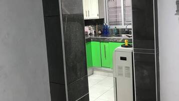 Una cocina moderna con baldosas blancas y negras, armarios verdes y un refrigerador blanco.