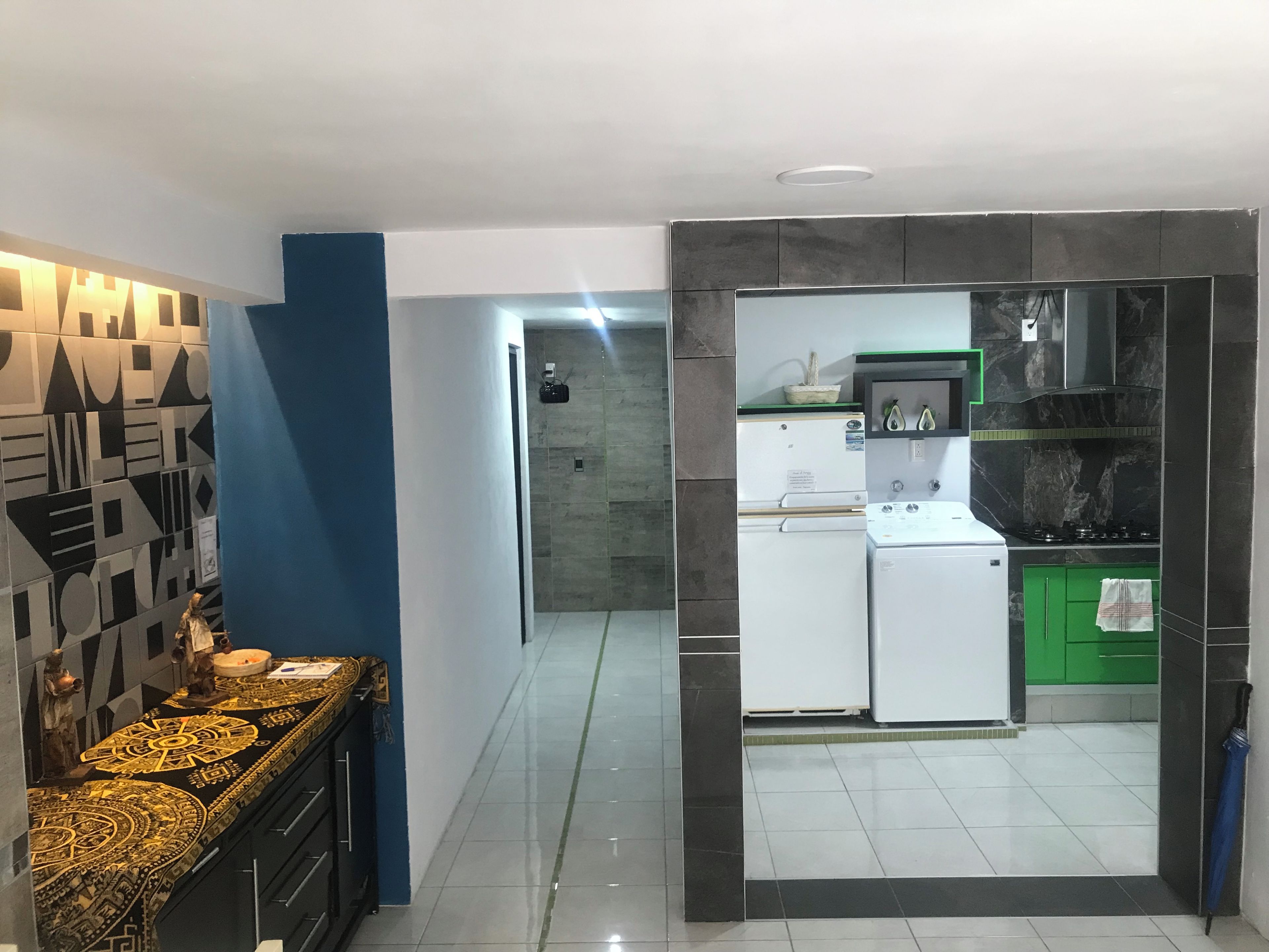 Eine moderne Küche mit Kühlschrank, Herd und grünen Schränken.