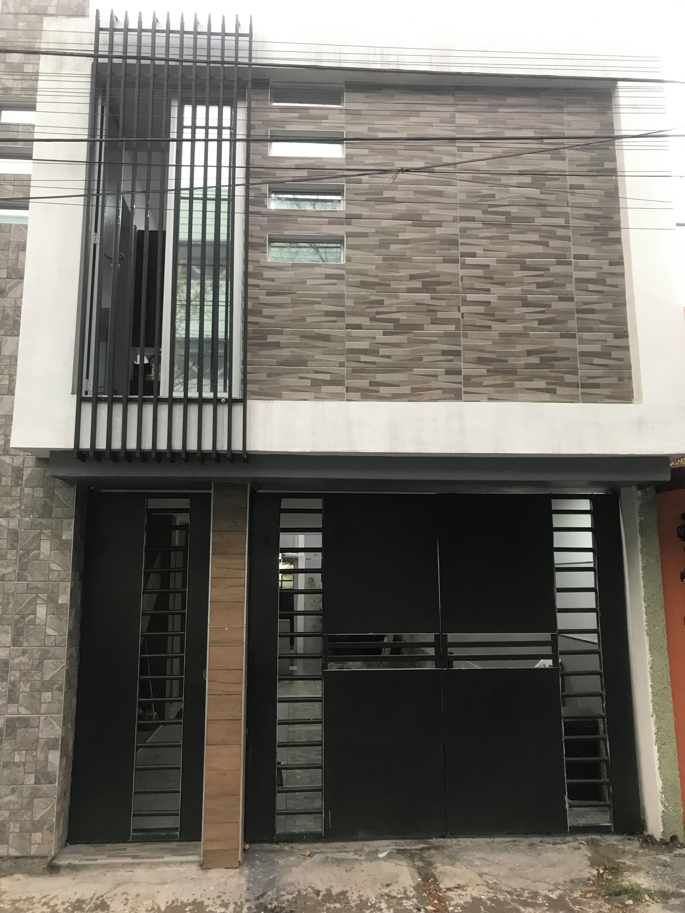 Un bâtiment moderne doté d’une porte de garage, d’une grande fenêtre et d’une clôture en métal.