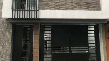 Un bâtiment moderne doté d’une porte de garage, d’une grande fenêtre et d’une clôture en métal.