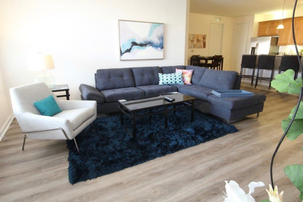 A modern living room with a sectional sofa, a small armchair, and a coffee table.