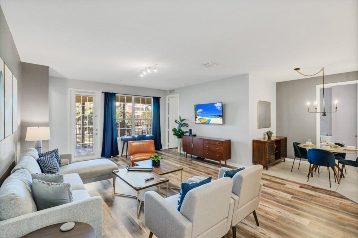 A modern living room with a sofa, coffee table, and a dining area with chairs and a table.