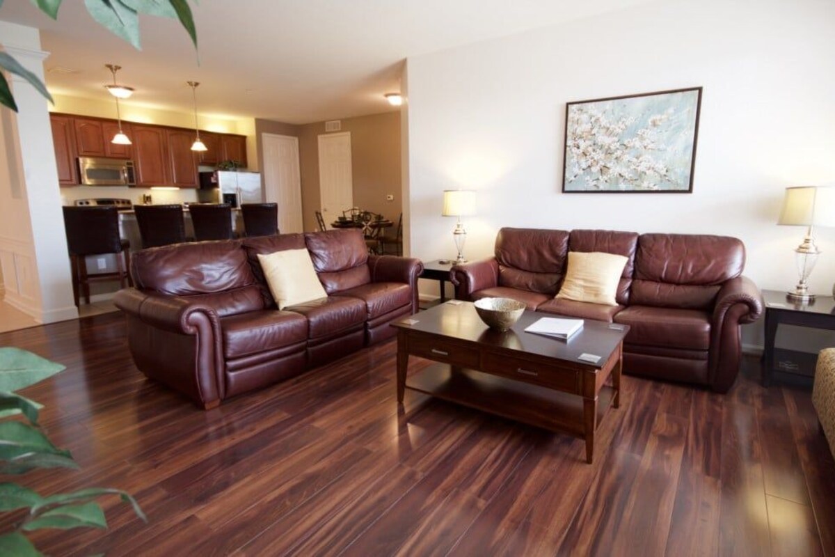 A living room with a brown leather sofa set, a wooden coffee table, and a painting on the wall.