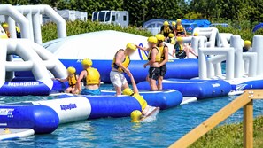 An inflatable water obstacle course with participants wearing life jackets and helmets. - Grange Park 2-Bed Caravan, Sleeps 6 with Parking (Mablethorpe)