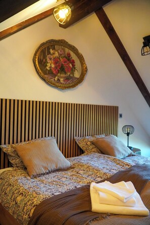 A bedroom with a wooden slat headboard, two pillows, a patterned bedspread, and a folded towel on the bed. - Imanje brodara Tome - Hot Tub, Garden, WiFi (Lekenik)