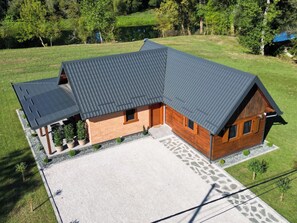 A two-story wooden house with a sloped roof, a covered porch, and a paved driveway. - Imanje brodara Tome - Hot Tub, Garden, WiFi (Lekenik)