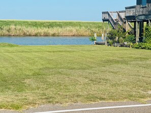 A grassy area with a wooden structure and a body of water in the background.