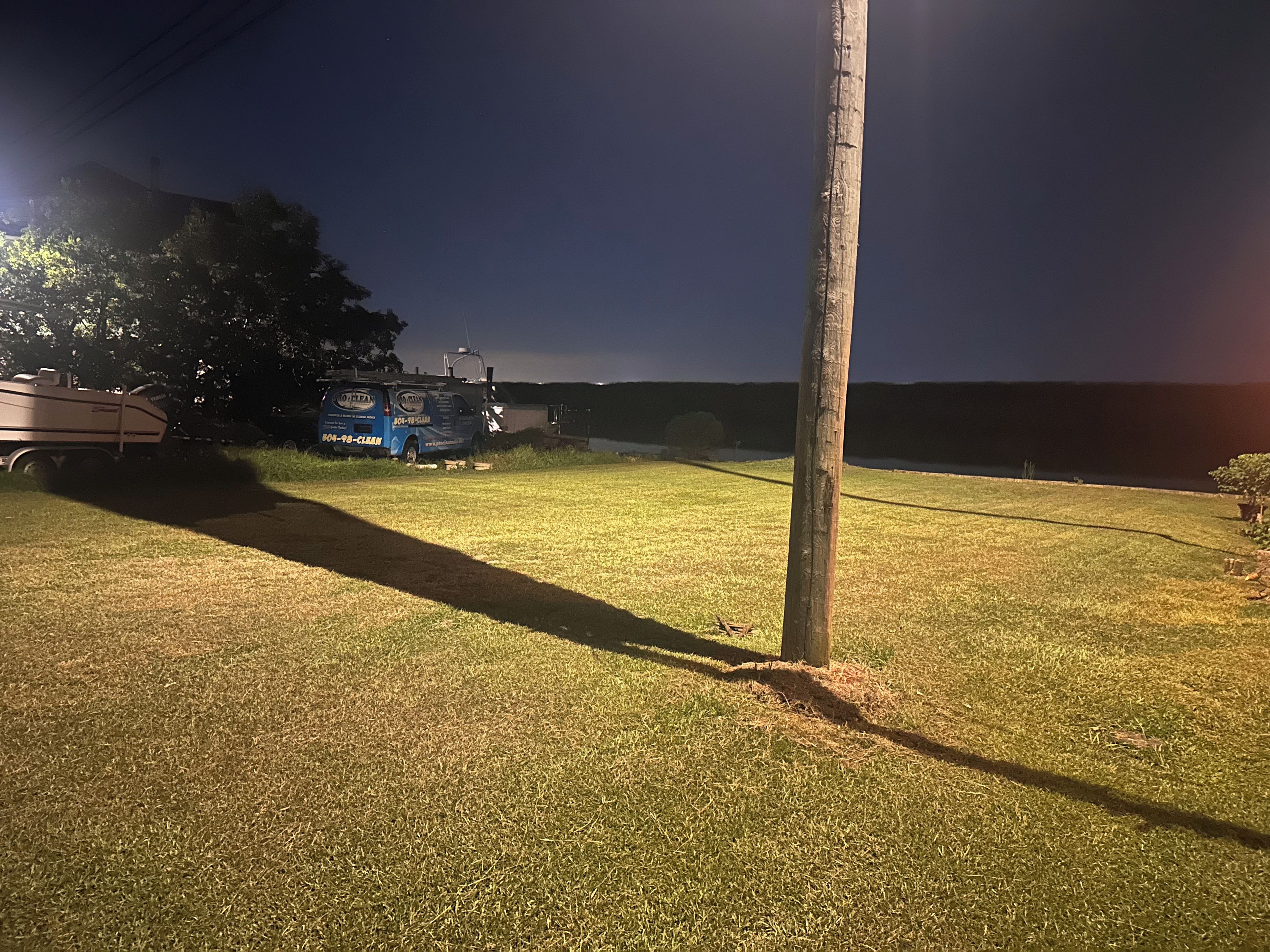 A grassy area with a parked van and a tree.