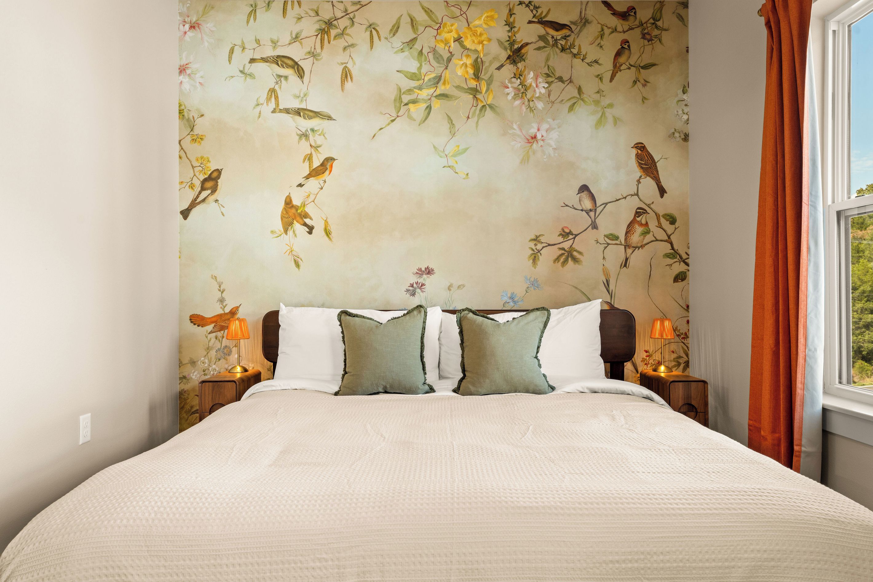 A closer look at the enchanting hand-painted feel of the bird-and-botanical mural, creating a peaceful garden-inspired backdrop for the plush king bed.