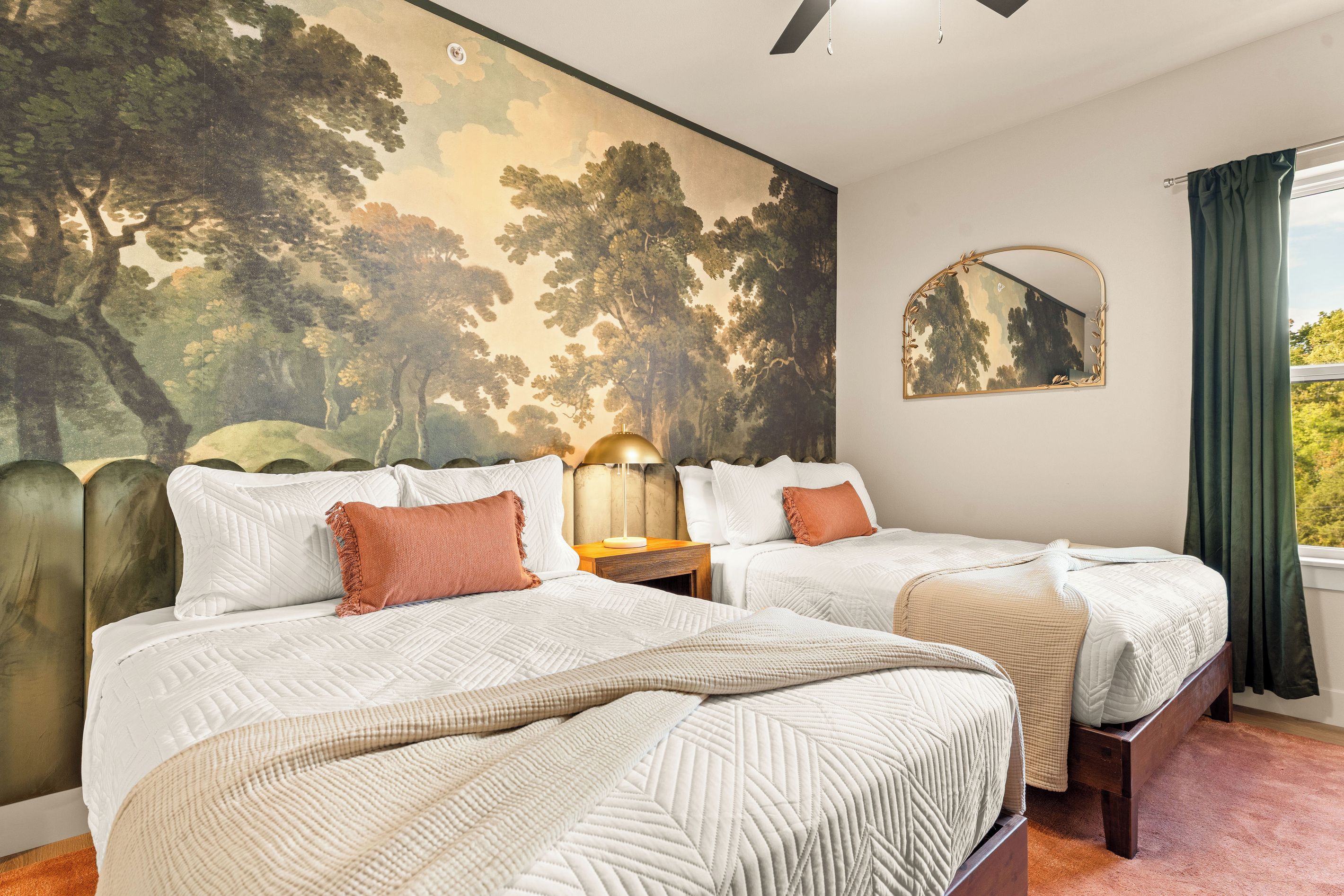 Woodland Double Bedroom
    Two comfortable beds rest beneath a dramatic woodland mural, creating a cozy forest-inspired retreat with crisp linens, warm coral accents, and plenty of room to unwind.