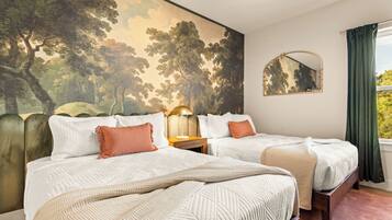 Woodland Double Bedroom
Two comfortable beds rest beneath a dramatic woodland mural, creating a cozy forest-inspired retreat with crisp linens, warm coral accents, and plenty of room to unwind.