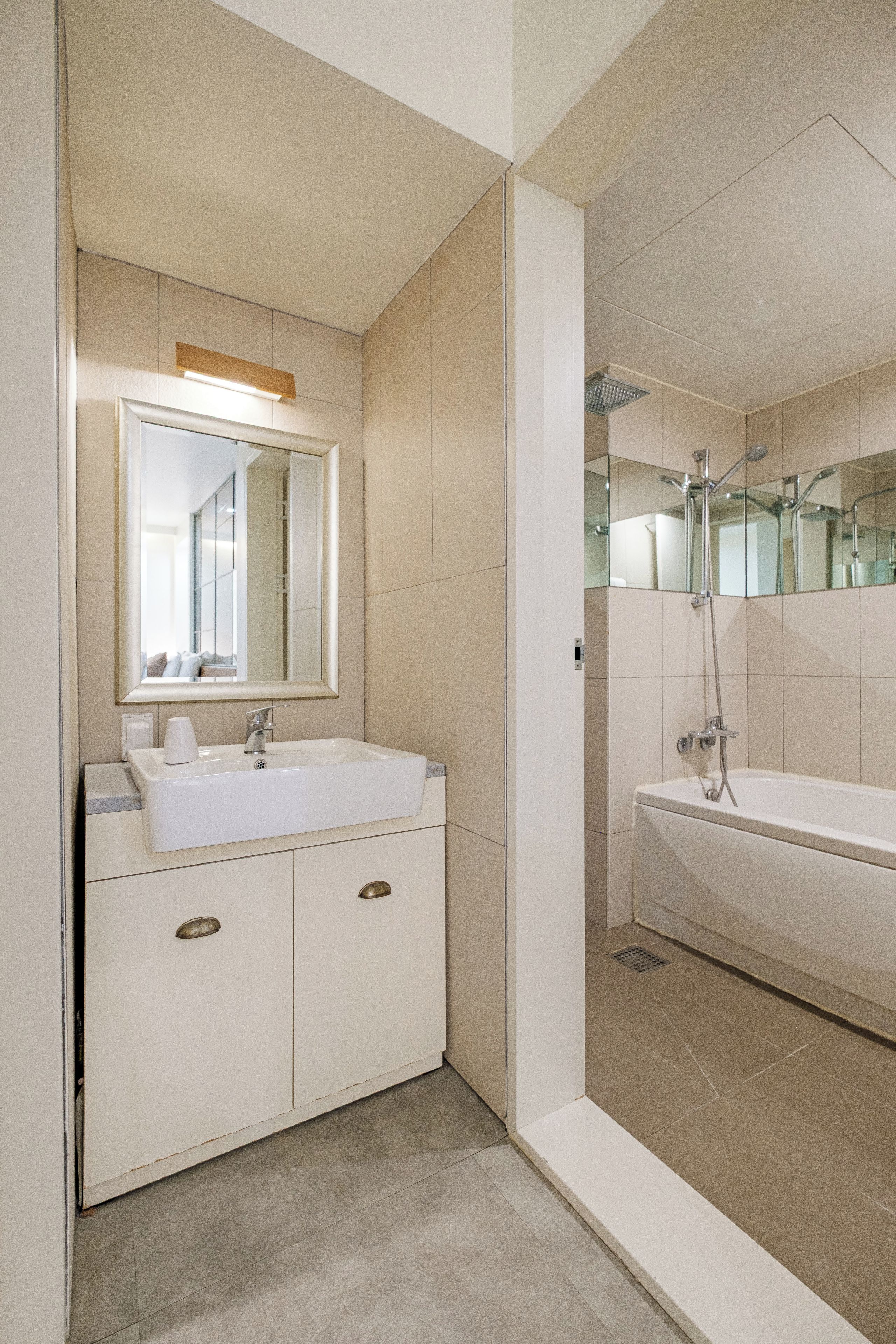 Un baño moderno con un lavamanos blanco, espejo y bañera.