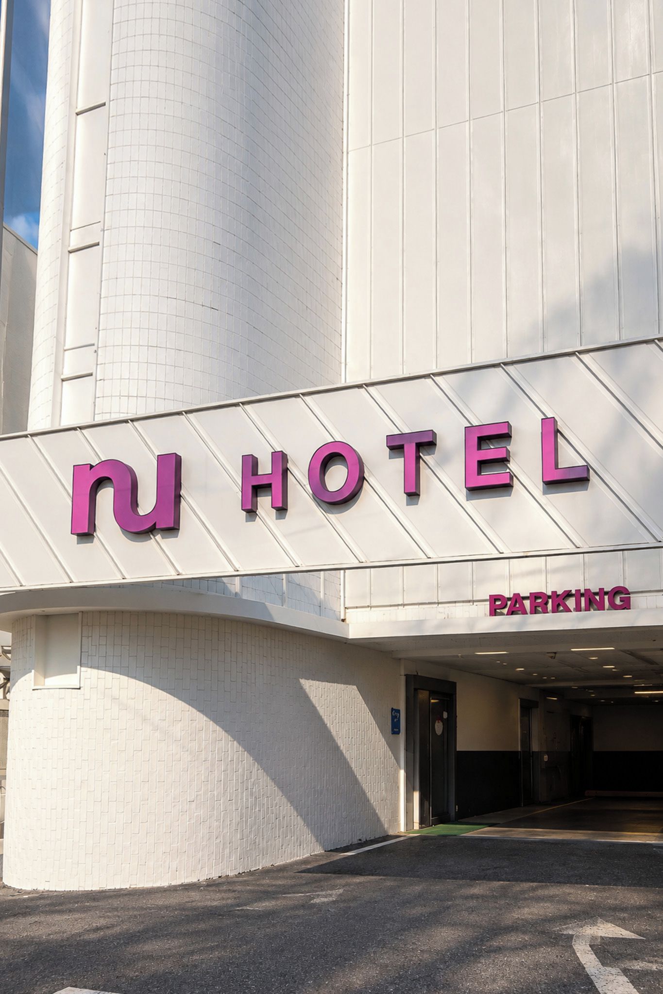 L'ingresso di un hotel con un'insegna ben visibile che recita 'HOTEL' e un'insegna sottostante con la scritta 'PARKING'.