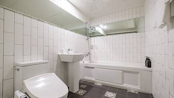 Un bagno con pareti in piastrelle bianche, un WC bianco, un lavandino e una vasca da bagno.