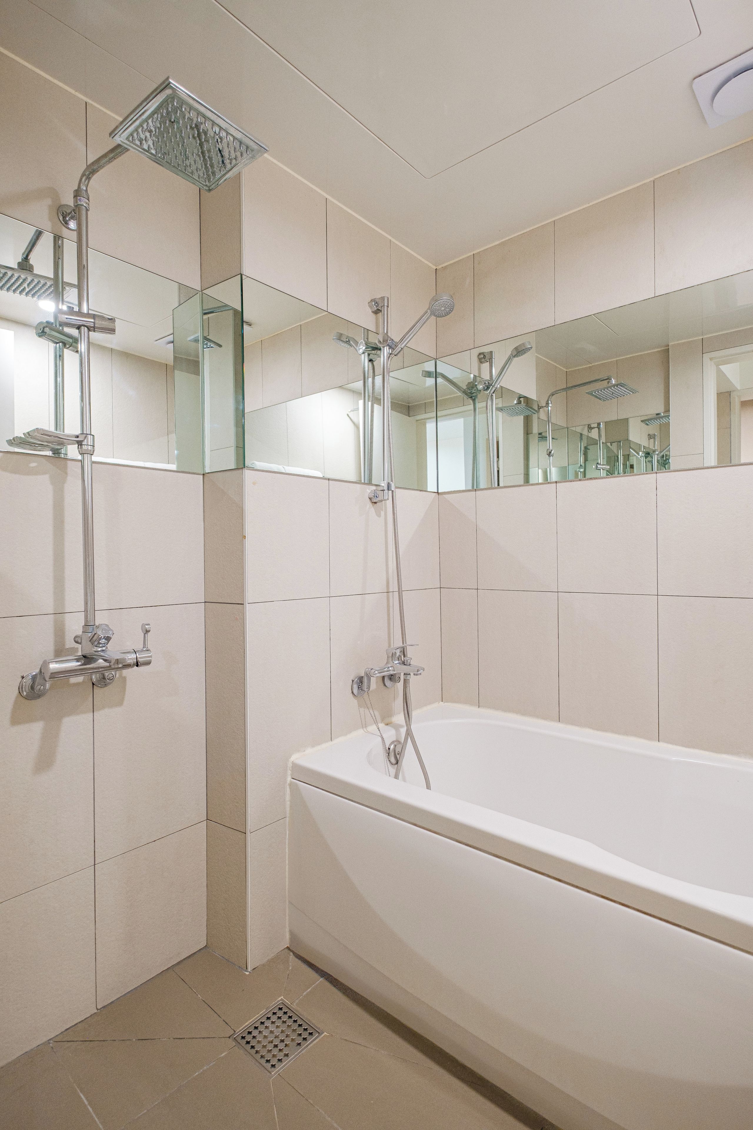Un baño moderno con bañera, ducha con cabezal de ducha de mano y mampara de vidrio.