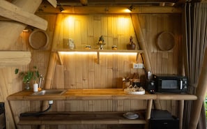 A rustic wooden kitchen with a built-in microwave, a sink, and a shelf with kitchen utensils.